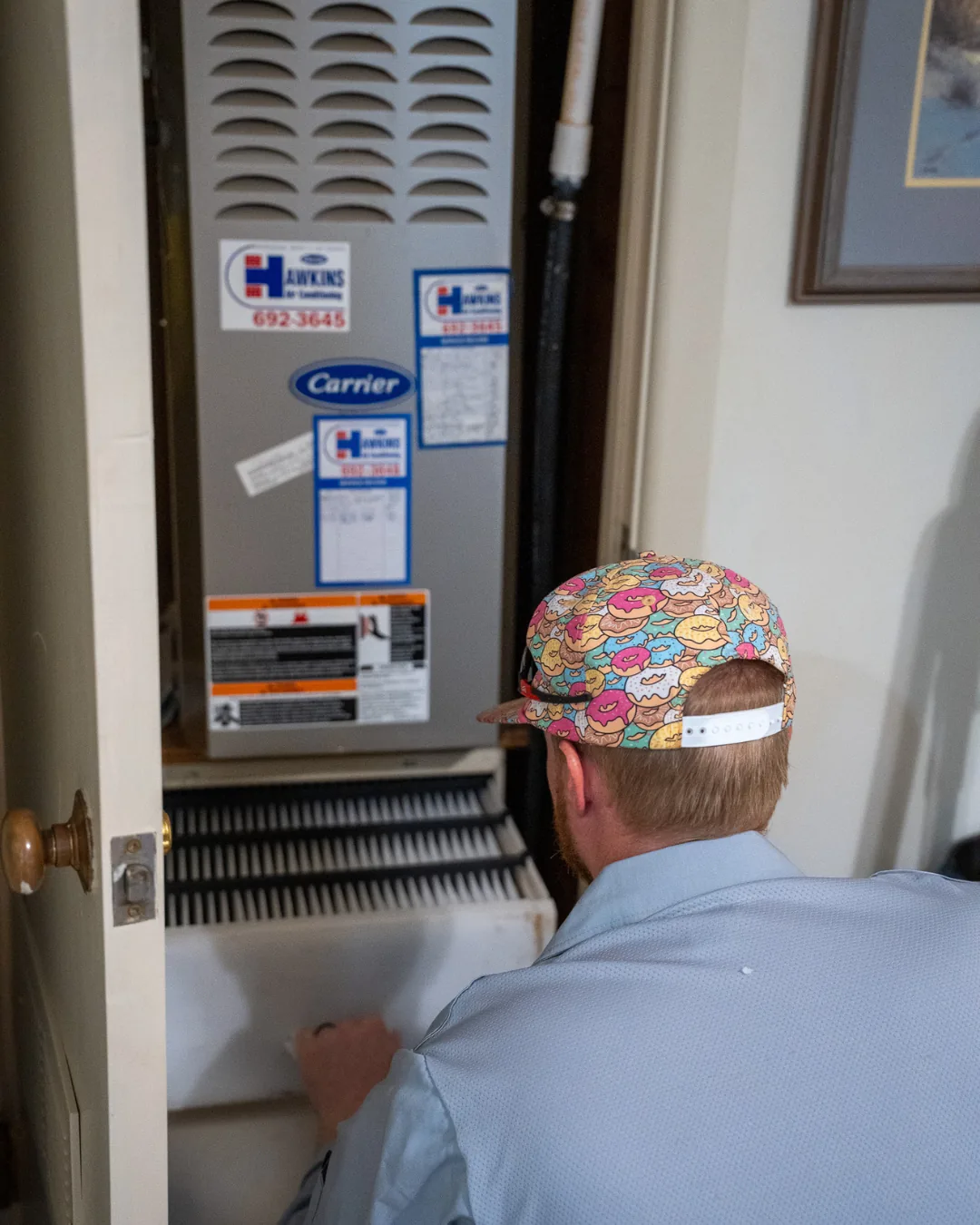 Hawkins technician servicing an indoor Carrier air handler